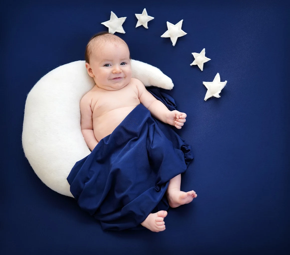 Smiling baby posed with moon and stars set during a professional baby photography session near McAllen, TX