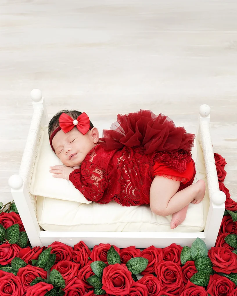 Newborn baby sleeping peacefully surrounded by roses during a professional photography session with Adrisabel Photography near McAllen, Texas