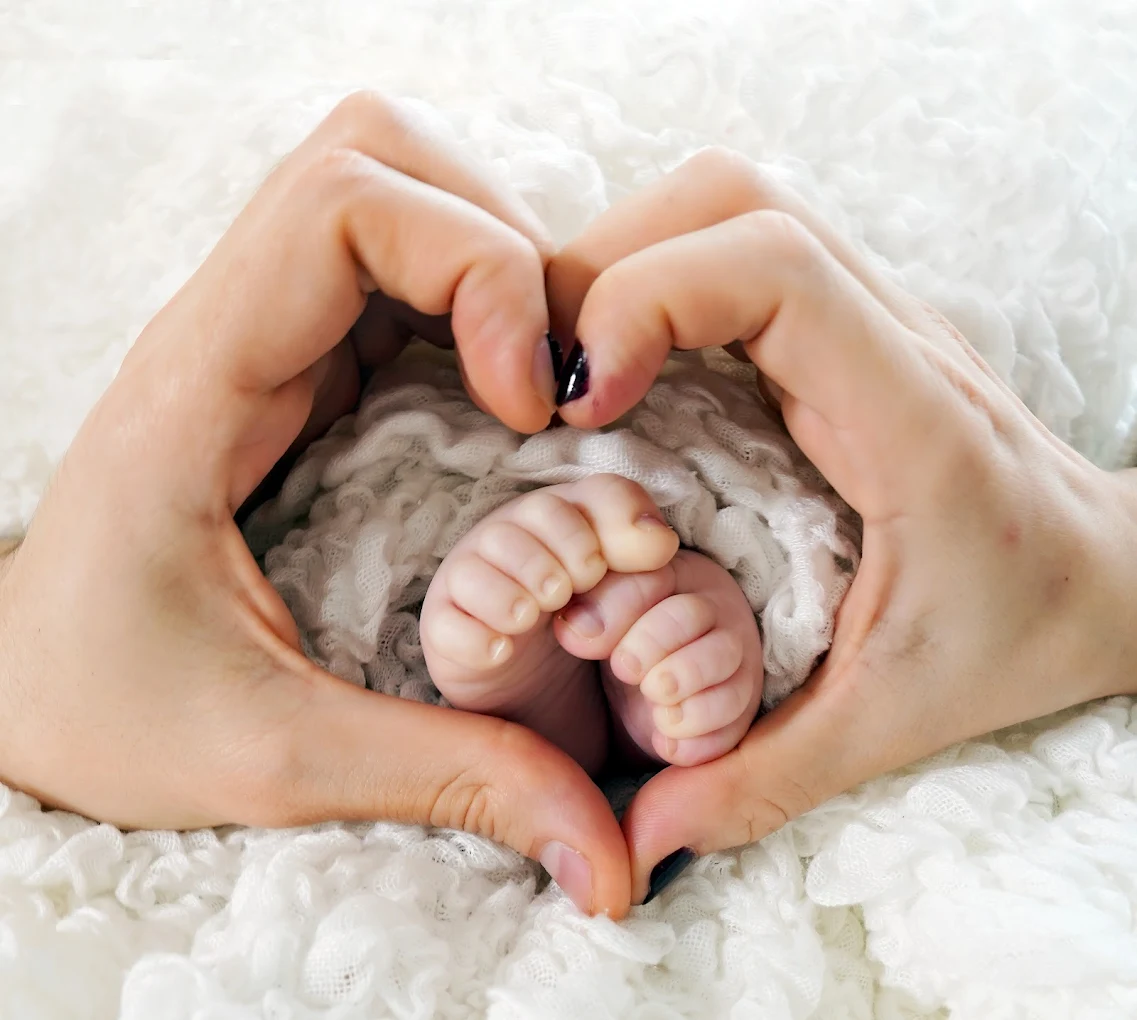 Parents hands gently holding baby feet, representing the connection between expecting parents and their baby at Adrisabel Photography